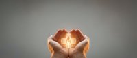 Hands cupping glowing light bulb symbolizing innovation, ideas, and sustainable energy solutions for business and environmental concepts.