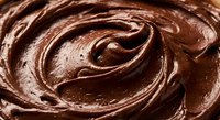 Rich creamy chocolate frosting with smooth swirls and glossy texture for baking and dessert preparation.