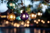 Colorful ornate glass lanterns hanging outdoors with warm glowing lights creating magical evening ambiance for restaurants and garden parties.