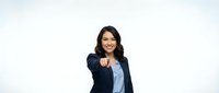 Professional Asian businesswoman in navy blazer pointing forward with confident smile on white background for corporate presentations and marketing materials.