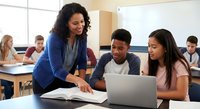 Female teacher with curly hair helping diverse students with laptop in modern classroom. Educational mentoring and academic support concept.