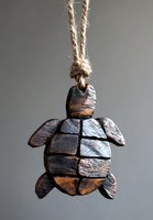Rustic wooden sea turtle pendant on natural twine rope against gray background, featuring carved segments and weathered texture for coastal home decor.