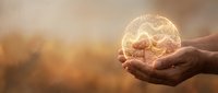 Young adult hands holding glowing brain symbol against warm sunset background, representing innovation, intelligence, and mental health awareness for educational and wellness content.