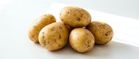 Fresh organic potatoes with natural skin spots isolated on white background for cooking and food design projects.