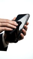 Male hand holding black smartphone with microfiber cloth for screen cleaning and maintenance. Isolated on white background, ready for design use.