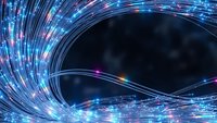 Abstract digital fiber optic light streams creating dynamic swirling motion with glowing particles and energy flow on dark background for technology concepts.