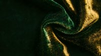 Luxurious metallic fabric with golden and emerald green shimmer creating elegant waves and folds for premium fashion and textile design projects.