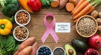 Healthy nutrition and wellness concept with pink ribbon surrounded by fresh vegetables, fruits, nuts and seeds on wooden background for cancer awareness.