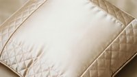 Cream-colored quilted pillow with diamond stitching pattern on neutral background, suitable for home decor, bedding, and interior design projects.