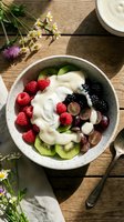 Healthy breakfast bowl with fresh berries, kiwi slices, yogurt and nuts on rustic wooden table. Nutritious morning meal with organic fruits and dairy.