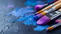 Paint brushes with vibrant blue and purple pigments on dark textured surface, artistic close-up showing brush bristles and mixed paint powder for creative projects.