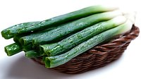 Fresh green cucumbers with water droplets arranged in a woven brown basket on white background, suitable for food, grocery, and culinary design projects.