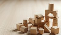 Natural wooden building blocks scattered on light surface for educational play and creative construction activities.