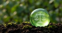 Crystal sphere with scales of justice symbol on soil representing environmental law and sustainability balance in nature.
