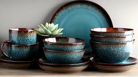 Handcrafted ceramic dinnerware set in teal and brown with speckled glaze finish featuring bowls, plates, and cups with succulent plant decoration.
