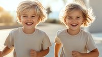 Joyful Caucasian twin children with blonde hair running and laughing outdoors in natural sunlight wearing white t-shirts, expressing pure happiness and energy.