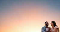 Diverse couple enjoying romantic sunset moment outdoors, man and woman gazing at each other against golden sky backdrop for relationship and lifestyle content.