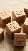 Wooden blocks with engraved smiley faces scattered on burlap fabric, conveying joy, positivity, and happiness concepts for business or wellness projects.
