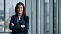 Confident businesswoman with crossed arms smiling in modern office with city view. Professional corporate executive portrait for business success concepts.