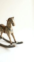 Vintage wooden rocking horse with weathered paint and rustic charm on neutral background for nostalgic childhood memories and antique toy collections.
