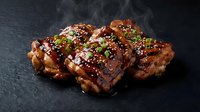 Grilled pork ribs with glossy barbecue glaze, sesame seeds and fresh herbs on dark slate background with steam for restaurant menu design.