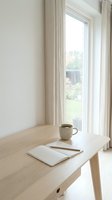 Minimalist wooden desk with coffee cup and notebook by bright window in modern home office workspace for productivity and remote work.
