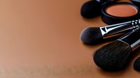 Professional makeup brushes and cosmetic powder on brown background, beauty industry concept with soft focus and copy space for text placement.