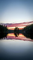 Serene lake at sunset with vibrant red and orange sky reflecting on calm water, surrounded by evergreen forest trees, ideal for nature and landscape backgrounds.