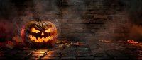 Carved jack-o-lantern with glowing face sits on ground against brick wall with dramatic orange and red lighting, suitable for seasonal marketing and holiday promotions.
