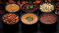 Assorted dips, sauces and nuts in black bowls on dark wooden background. Mediterranean appetizers with chickpeas, almonds, cashews and kidney beans.