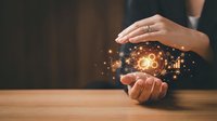 Female hands protecting glowing lightbulb with digital network connections symbolizing innovation, creativity and business idea protection concept.