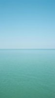 Serene seascape with calm turquoise waters meeting clear blue sky at horizon. Minimalist coastal scene with smooth ocean surface and peaceful atmosphere for relaxation and travel concepts.
