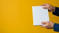 Male hand holding blank white box against yellow background, suitable for product packaging mockups, branding presentations, and commercial advertising campaigns.