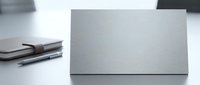 Closed silver laptop on white desk with notebook and pen, workspace setup for business, technology, and remote work environments.
