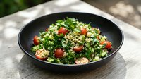 Tabbouleh salad with fresh parsley, tomatoes, and bulgur wheat in black bowl on wooden surface, Mediterranean cuisine.