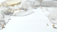 Elegant white wedding invitation mockup with delicate lace details, champagne glasses and romantic table setting for luxury bridal stationery design.