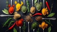 Colorful spices and herbs in vintage spoons on dark background. Culinary ingredients for cooking, seasoning and flavoring dishes in kitchen.