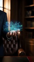 Businessman in dark suit holding glowing holographic display with gears, wind turbines, solar panels, and rising charts representing renewable energy, sustainability, and green technology innovation.
