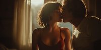 Intimate couple sharing passionate kiss in warm golden sunlight streaming through window creating romantic atmosphere for relationship content.