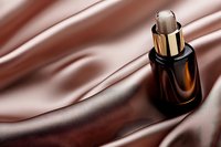 Luxury brown glass dropper bottle on silky fabric background with elegant folds and shadows, cosmetic product presentation for skincare and beauty industry.