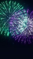 Spectacular fireworks display with vibrant green and purple bursts illuminating dark night sky for celebration events and holiday festivities.