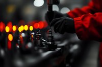 Close-up of DJ mixer controller with glowing red lights in nightclub atmosphere, hand adjusting fader knob during performance, selective focus on equipment.