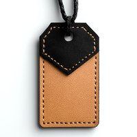 Leather luggage tag in black and tan colors with contrast stitching and braided cord on white background, isolated for commercial design use.
