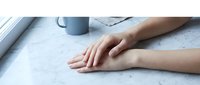 Woman hands resting on white marble surface near window with soft natural light creating calm peaceful atmosphere for relaxation and mindfulness.