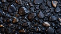 Wet black stones with water drops creating natural pattern on dark background, smooth polished river rocks texture with reflective surface and droplets.