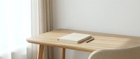 Wooden desk with open notebook and pen in bright minimalist workspace with natural light from window.