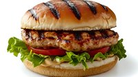 Grilled chicken burger with fresh lettuce, tomato and mayonnaise on toasted bun with grill marks, isolated on white background for menu and advertising.