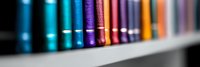 Colorful book spines arranged in rainbow order on library shelf, with selective focus creating artistic blur effect, capturing modern educational atmosphere.
