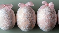 Elegant Easter eggs decorated with delicate white lace and pink satin bows on soft green background, perfect for spring holiday celebrations.