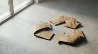 Crumpled kraft paper bags scattered on concrete floor near window, depicting waste, recycling, or storage concepts for design projects.